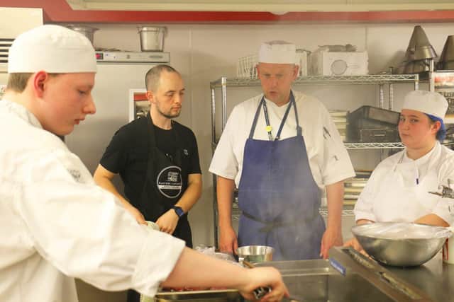 Lewis prepares food in the kitchens assisted by chef tutor Mark Jones and Level 3 students