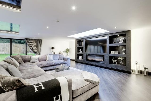 This is a closer look at the comfortable living area within the open-plan space. It comes complete with a media wall and fireplace, two aluminium skylights and aluminium bi-fold doors that lead out to the back garden.