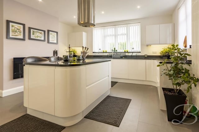 The sleek kitchen comes complete with modern wall and base units, a quartz work surface and inset sink with mixer tap above. A centre island houses a five-ring ceramic hob and stainless steel extractor fan above.