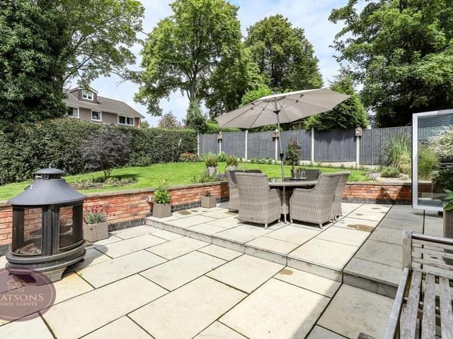 A close-up of the Indian stone paved patio in the back garden, which is the ideal spot for relaxing or entertaining. Enclosed by low brick walls, it is fitted with outdoor lighting, external power sockets and water supplies, and steps leading up to the lawn.