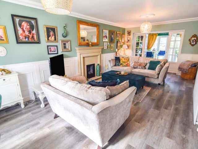 Moving on now to the main body of the house, and this large lounge, with its feature fireplace and wooden-effect flooring. Double doors lead to the dining room.