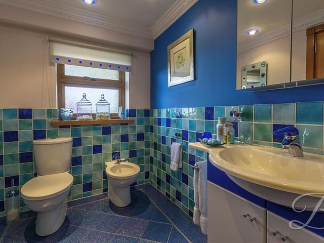 Blue is certainly the colour in the en suite shower room.This second shot reveals blue, laminated tiled flooring, a low-flush WC and a bidet.