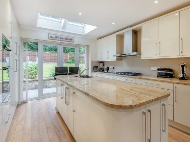 Other features of the kitchen include French doors that lead to the garden, a wood-effect laminate floor and a five-ring gas hob with stainless extractor hood above.