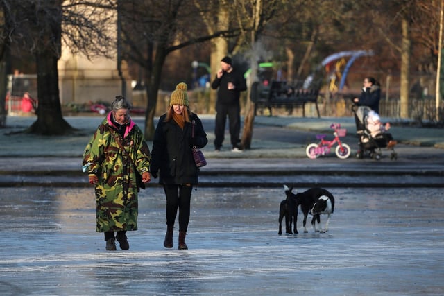 People walk on a frozen pond at Victoria Park in Glasgow.