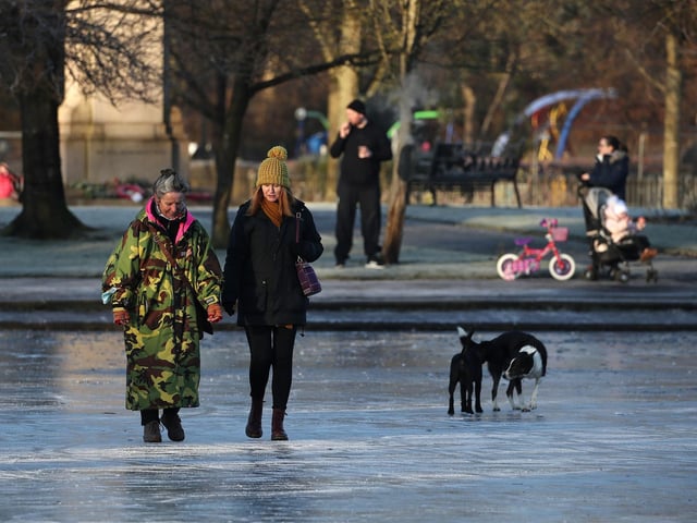 People walk on a frozen pond at Victoria Park in Glasgow.