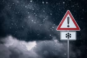 Warning sign in front of cloudy sky with snowfall. Photo by getty images.