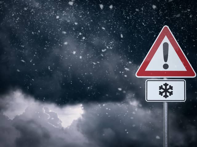 Warning sign in front of cloudy sky with snowfall. Photo by getty images.