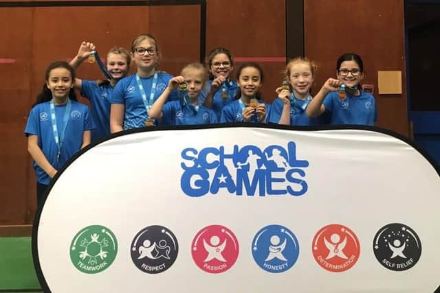 The year five girls basketball team show off their medals.