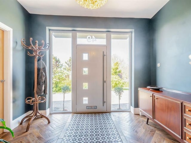 Let's rake a look inside the substantial dormer bungalow. Through the composite front door, with floor-to-ceiling double-glazed windows to each side, and into the entrance hall that has a herringbone wood floor and a central tiled feature.