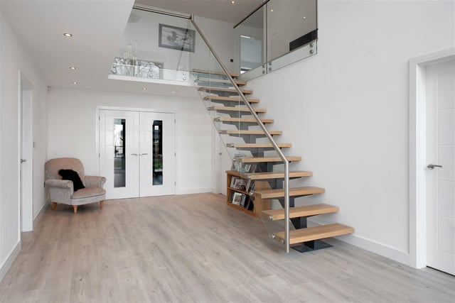 There is a 16ft 4in atrium vaulted ceiling rising up to the first-floor galleried landing with full height floor-to-ceiling glazing, underfloor heating and a bespoke, modern floating staircase.