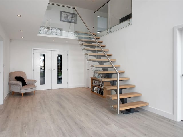 There is a 16ft 4in atrium vaulted ceiling rising up to the first-floor galleried landing with full height floor-to-ceiling glazing, underfloor heating and a bespoke, modern floating staircase.