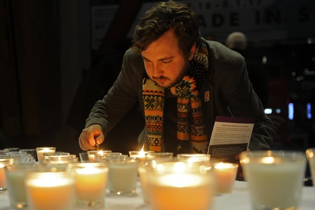 James Collister lights a candle at a candlelit vigil in the Winter Gardens, Sheffield for Holocaust Memorial Day in January 2017