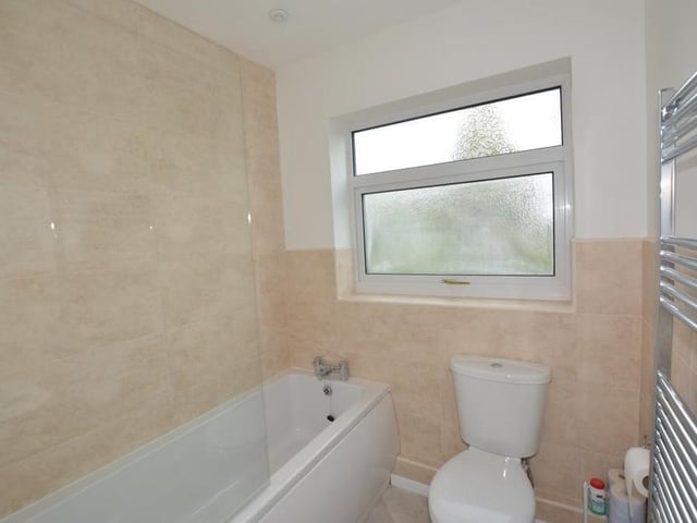 The main bathroom sits on the ground floor of the Honing Drive property. It is newly fitted with a white three-piece suite that comprises a panelled bath with Triton shower over, a pedestal wash hand basin, low-level WC, half-tiled walls, a heated towel-rail and downlighting.