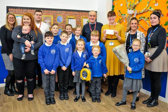 In December 2019, Holly Younger, of Leon’s Legacy, fourth from right,  holds a cheque for £200 donated by Mapplewells Primary and Nursery School, while children hold the new defibrillator now installed at the school.