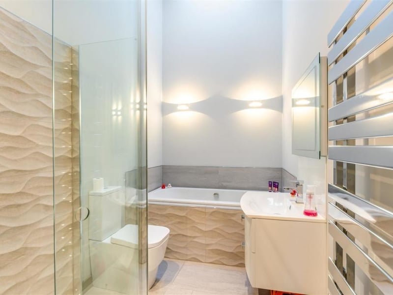 The en suite to the master bedroom is a contemporary four-piece suite with chrome fittings. Marvel at a tiled inset bath, a separate, tiled shower enclosure with wall-mounted 'rainfall' shower and extra handset, low-flush WC and wall-hung wash hand basin with mixer tap and two storage drawers beneath. A fitted, heated mirror, tiled floor, underfloor heating, chrome, heated towel-rail, ceiling spotlights and skylight window complete an amazing space.