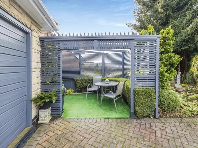 Nestled in a quiet corner of the garden is this splendid seating area under a pergola.