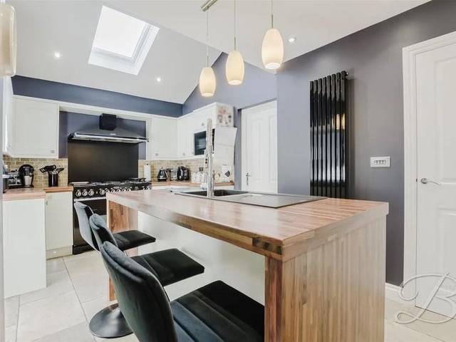 A bright and spacious kitchen, fully equipped with sleek gloss wall and base cabinets, an inset sink with drainer, and a striking central island. It also features built-in units and integrated appliances, including a Range master fridge/freezer, bosch microwave and provision for a large cooker. A Velux window enhances the natural light, with convenient access to the utility room and garage.