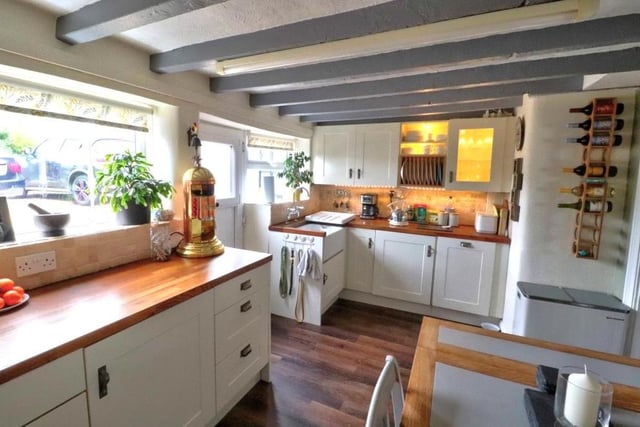 The dining kitchen from a different angle, showing a room full of character, with its ceiling beams and Karndean flooring. It is fitted with a range of cream wall and base units with matching drawers, while a stable door leads to the back garden.