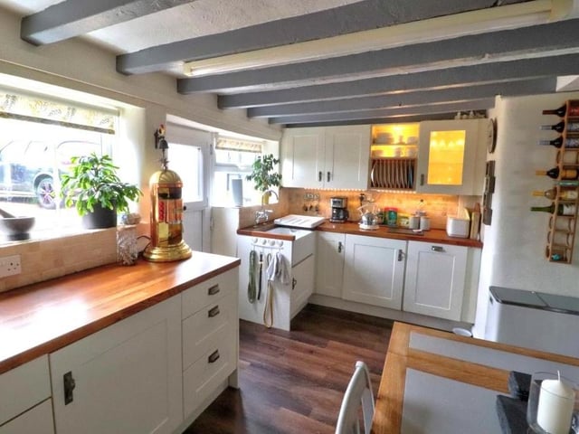 The dining kitchen from a different angle, showing a room full of character, with its ceiling beams and Karndean flooring. It is fitted with a range of cream wall and base units with matching drawers, while a stable door leads to the back garden.
