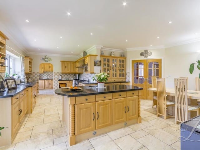 Moving on now to the spectacular kitchen, which boasts an open-plan layout with a range of Canadian Maple fronted wall and base units, giving plenty of storage, granite work surface over, central island and inset stainless steel sink with a mixer tap above.