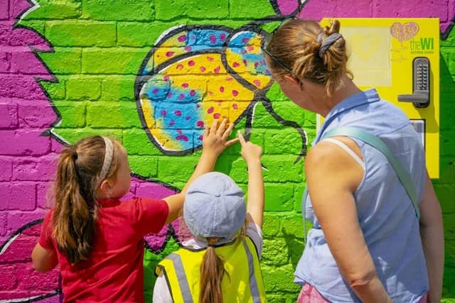 pupils adding their fingerprints to a ladybird feature on the mural. Courtesy of Bolsover District Council