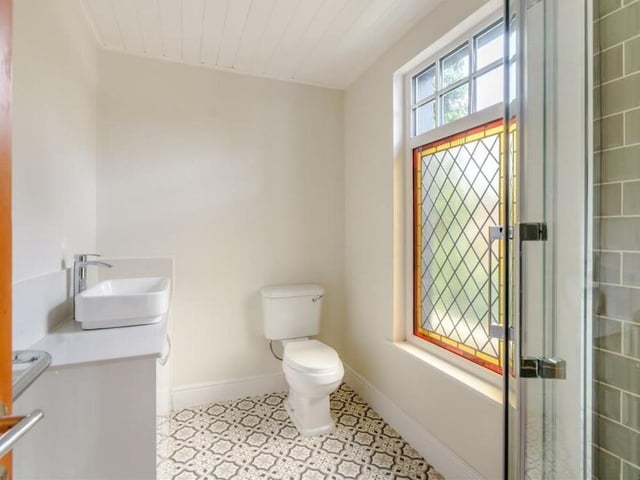 Here is the en suite bathroom to the master bedroom. It is a three-piece suite with chrome fittings and comprises a corner tiled shower cublcle, a vanity unit with inset wash hand basin and a low-flush WC. There are also quartz worktops, a storage cupboard, a tiled-effect vinyl floor and a nice stained glass window.