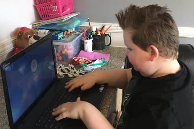 Alfie Chappell, who is nine, with his donated laptop to help him do his school work at home.