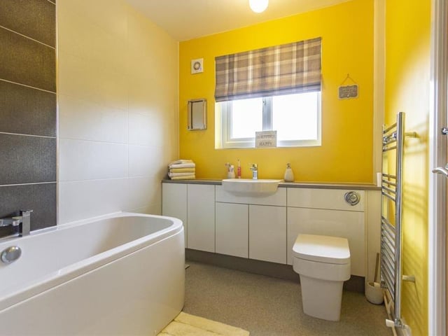 The family bathroom also sits on the ground floor and is fitted with a contemporary, white three-piece suite. It comprises a panelled bath with folding glass shower screen and mixer shower over, semi-inset wash hand basin with storage below and at the side, and a WC with concealed cistern. There's a chrome, heated towel-rail too.