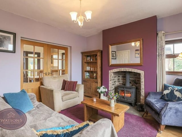The second reception room is this relaxing sitting room, which features another attractive fireplace, with inset multi-fuel burner, windows to the front and side, a wood-effect laminate floor, under-stairs storage and French doors leading to the kitchen/diner.