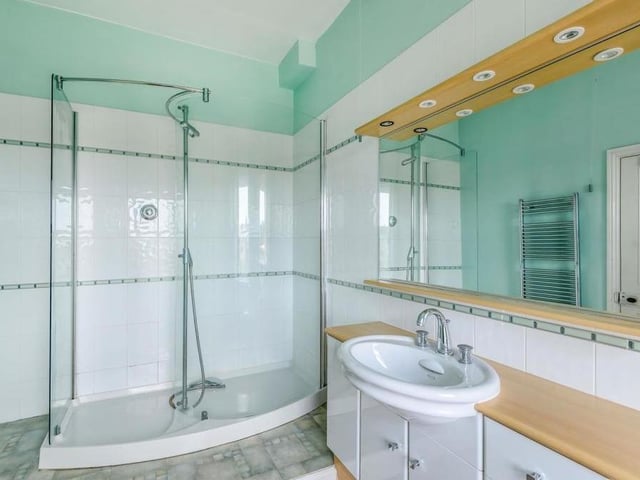 The master bedroom has access to this excellent en suite, which includes a large, tiled shower enclosure.There is also a vanity unit with inset wash hand basin and storage cupboards beneath, not to mention a striking mirror with inset spotlights.