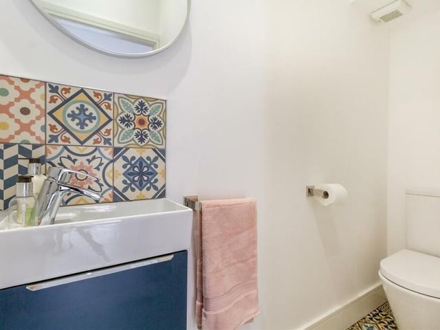 Completing our tour of the ground floor is this toilet, a two-piece white suite comprising a low-flush WC and vanity unit with inset wash hand basin, chrome waterfall mixer tap and storage cupboard beneath.