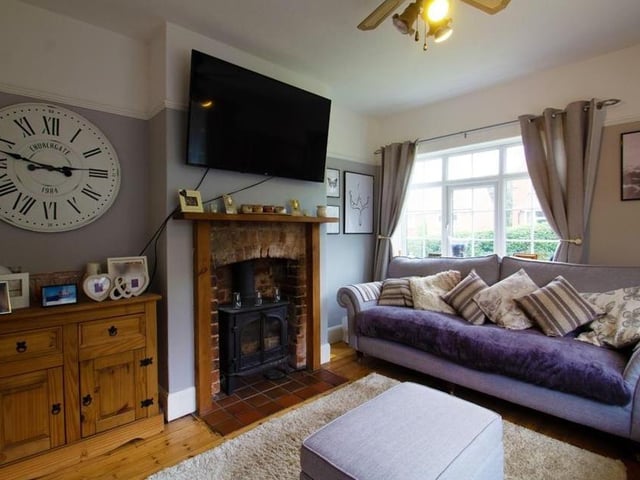 This is another view of the first reception room. It boasts an exposed-brick feature fireplace surround with a tiled hearth housing a log burner.