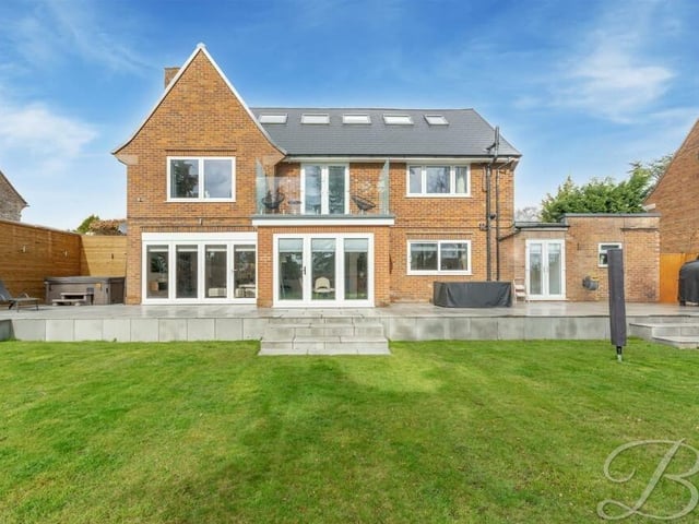 A view of the back of the £825,000 property, showing the balcony and the various doors that open out on to the patio and lawn.