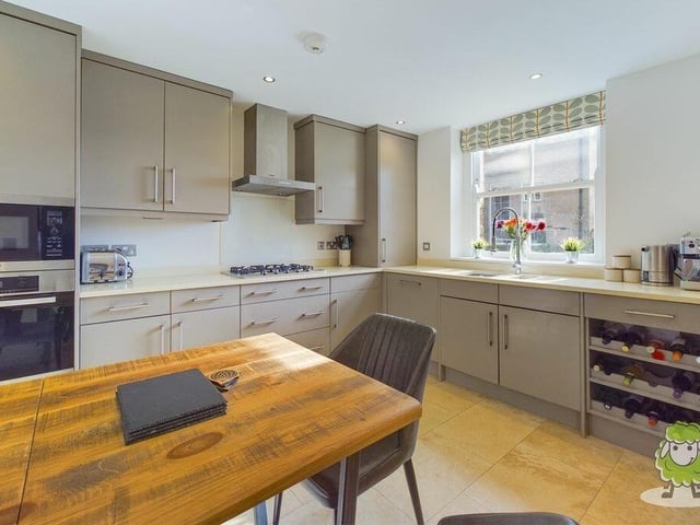 The kitchen features hand-crafted units with integrated appliances by Miele, a quartz worktop and a travertine, tiled floor