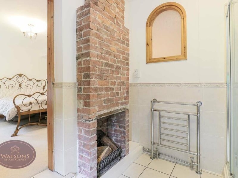 Unusually, the en suite shower room to the main bedroom includes an exposed brick fireplace.A three-piece suite comprises a corner shower cubicle with electric shower, pedestal sink unit and WC. There is also a chrome heated towel-rail.