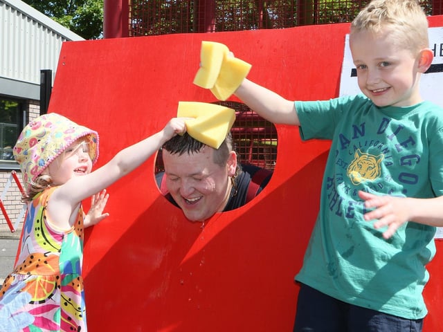 Finley and Esme Gardiner throwing wet sponges at firefighter Josh Harvey.