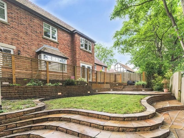 The rear garden is beautifully landscaped with a laid lawn, a patio seating area, and a second sheltered patio featuring a built-in BBQ—ideal for outdoor dining. Surrounded by established trees, shrubbery, and secure fencing, it offers a private and tranquil space.