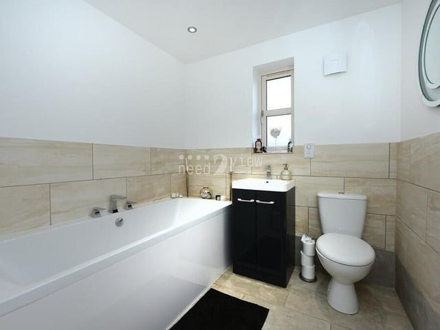 We round off our inspection of the first floor in the family bathroom. A white three-piece suite comprises a bath, wash hand basin, built into a vanity unit, WC and partly tiled walls.