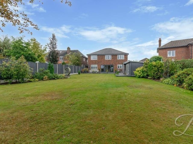 The rear garden is dominated by this extensive, well-kept lawn, surrounded by mature shrubs. There is also a summer house.