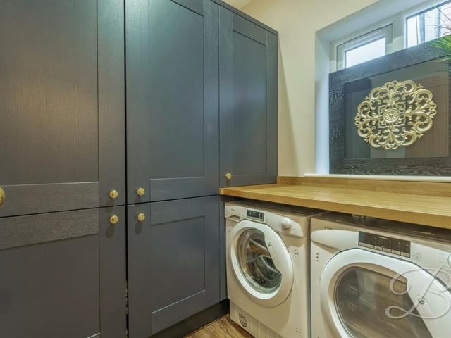 A colourful utility room has space and plumbing for a washing machine and tumble dryer. Fitted units match those of the kitchen, with worktop over.