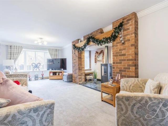 An expansive reception room with plush carpet flooring, central heating radiator and a box window to the front. Stunning brick feature wall which sets bock the gas fireplace, with windows either side.