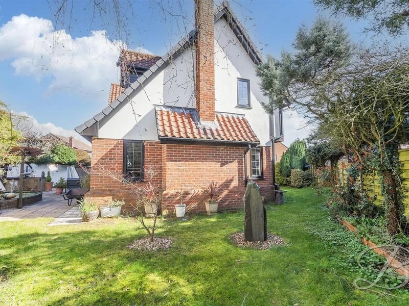 The rear garden features a well-maintained lawn and paved patio area.