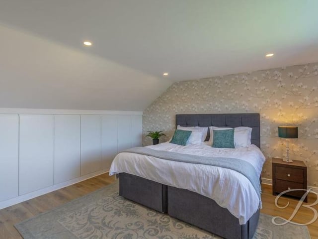 The master bedroom includes fitted storage, laminate flooring and downlights, and has access to an en suite shower room.