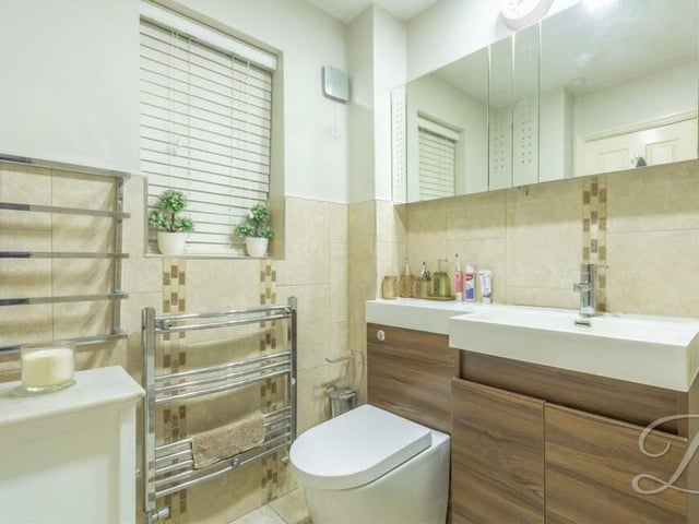 The sleek en suite shower room to the master bedroom includes a walk-in shower cubicle, low-flush WC, vanity hand wash basin and chrome, heated towel-rail
