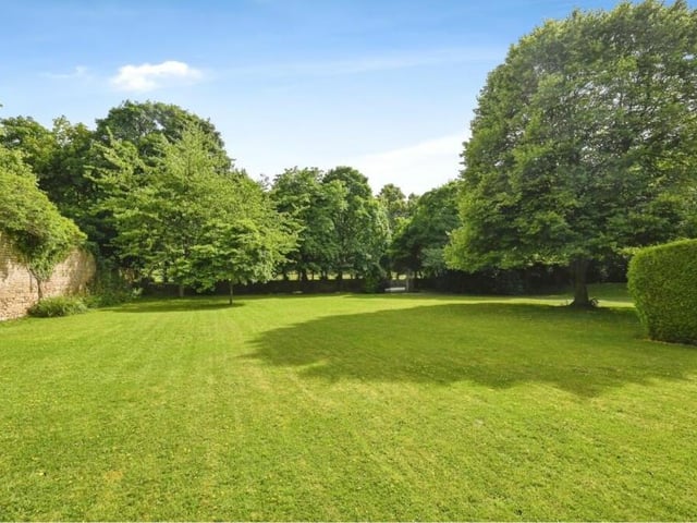 A view of the green and glorious gardens that provide the setting for the £120,000-plus apartment. Lawns and trees are enclosed within a stone boarder wall.