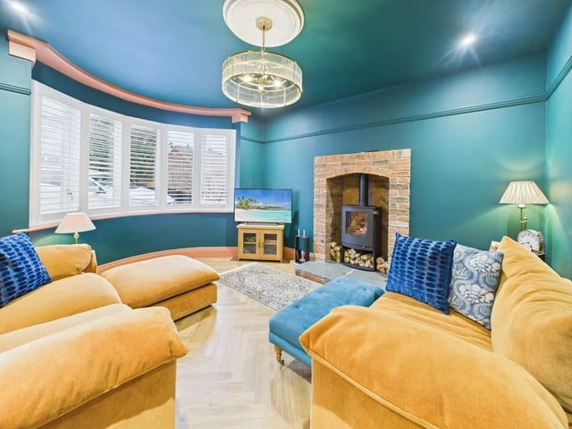The main lounge features a charming bay window with fitted shutters, a stylish fireplace with exposed brickwork, and a feature log burner, creating a warm and inviting atmosphere.