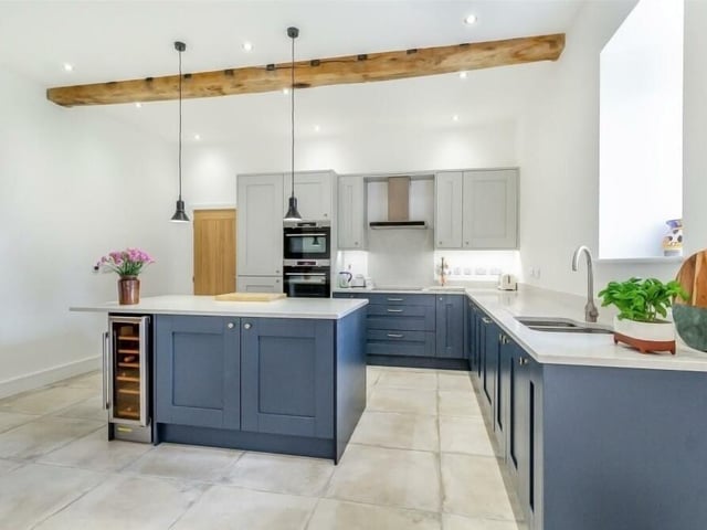 The dining kitchen at The Granary is a contemporary space that is part of a large open-plan area. Original beams to the ceiling give it plenty of traditional character, while quartz worktops, integrated appliances and a central island apply the modern touches.