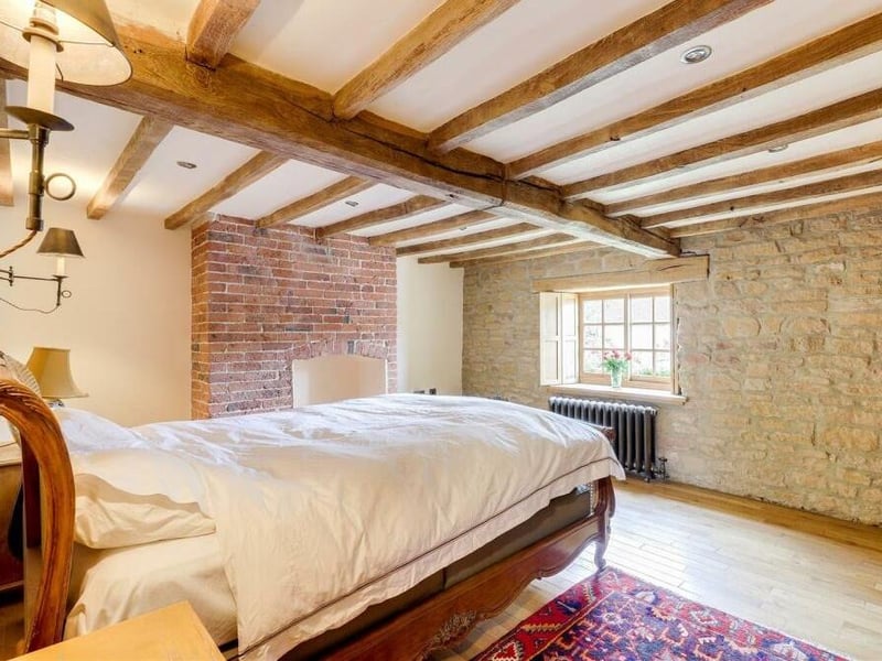 The character of the £550,000 cottage continues in the master bedroom on the first floor. Here you can see a feature exposed brick wall, a window with solid-oak frames and shutters, and an exposed-brick, recessed chimney-breast alcove.