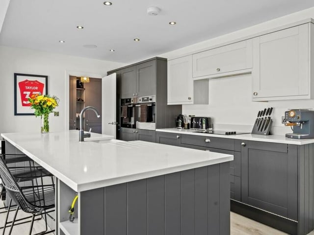 Among the modern kitchen's assets are an island, an integrated double oven, other high-spec integrated appliances, quartz worktops, an induction hob, a Belfast sink and a dishwasher.