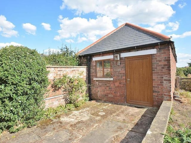 A closer look at the storage outbuilding in the garden. It is equipped with power and light and has a high vaulted ceiling, plus a flagstone floor.